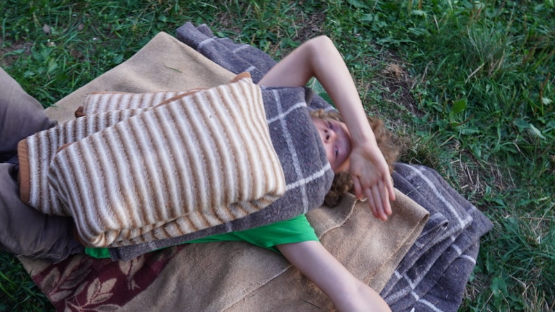 Ein Phönixjunge liegt in einem Stapel Wolldecken, mit denen später die Schwitzhütte eingedeckt wird